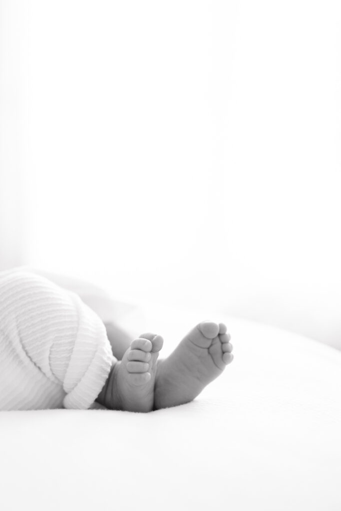 A black and white image of a newborn baby's feet. 