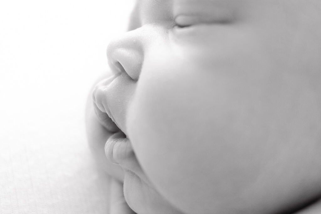 A black and white close up image of a baby's lips and cheeks. 