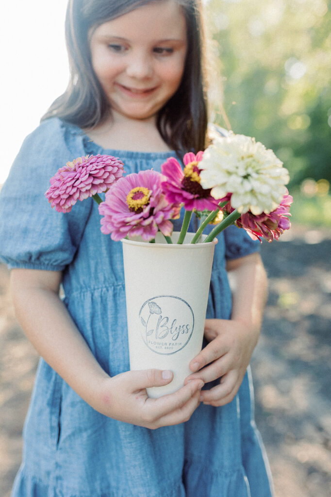 A close up of a girl holding a bouquet of flowers picked at Blyss flower farm in Grand Forks