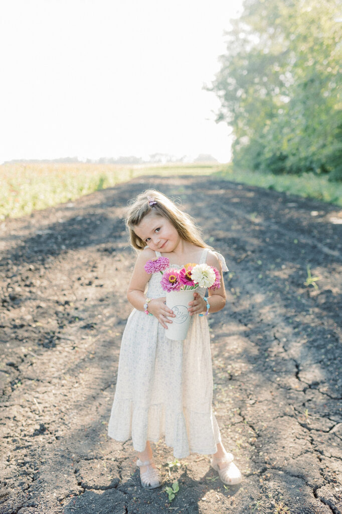 A young girl posing with the flowers she picked during her family photo session