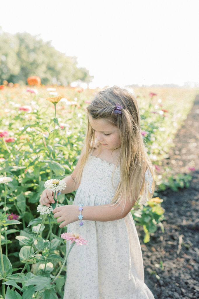 A young girl looking at wildflowers during her family photo session. 