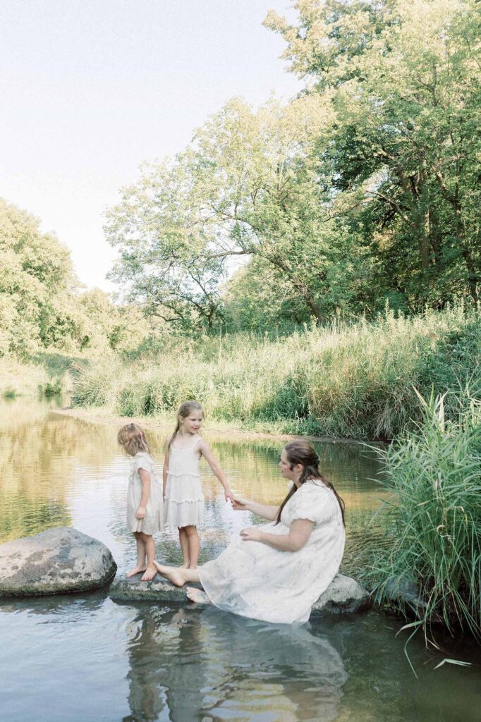 A mom sitting on rocks in the water at Turtle Creek State Park photography grand forks 