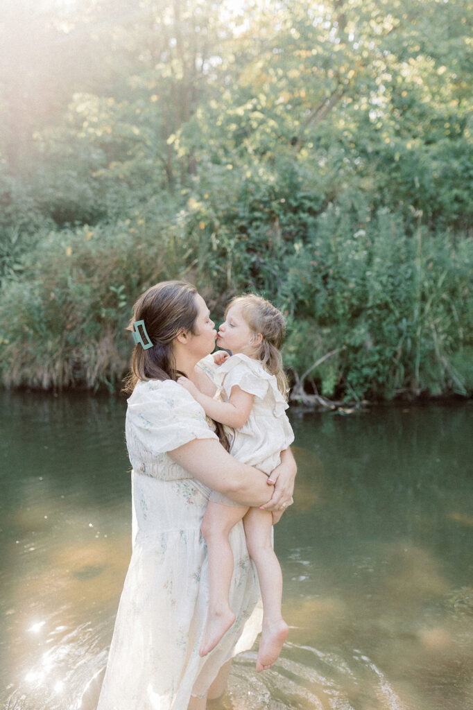 A mom gives her daughter a kiss while in the water during her grand forks photography session 