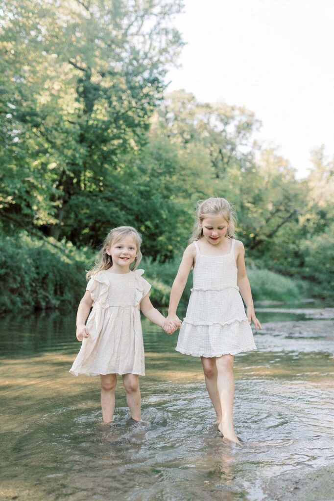Two sisters holding hands while playing in the water during their photography session at Turtle River State Park 