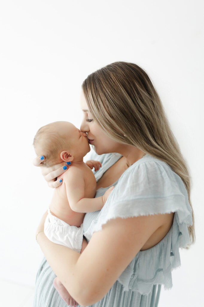 Mother in a flowing dress holding her newborn during a lifestyle photography session in Grand Forks ND.