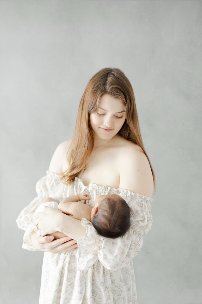 Newborn photography Grand Forks ND featuring a mom cuddling her baby in a timeless outfit.
