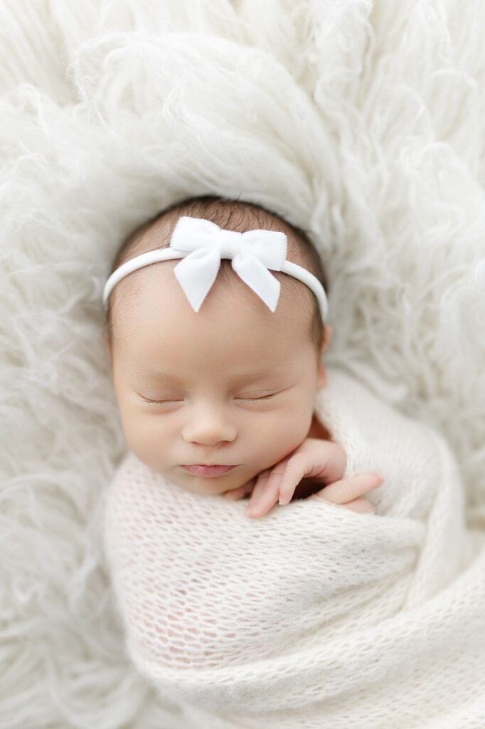 Close-up of baby wrapped in a light swaddle — simple styling for newborn photography.