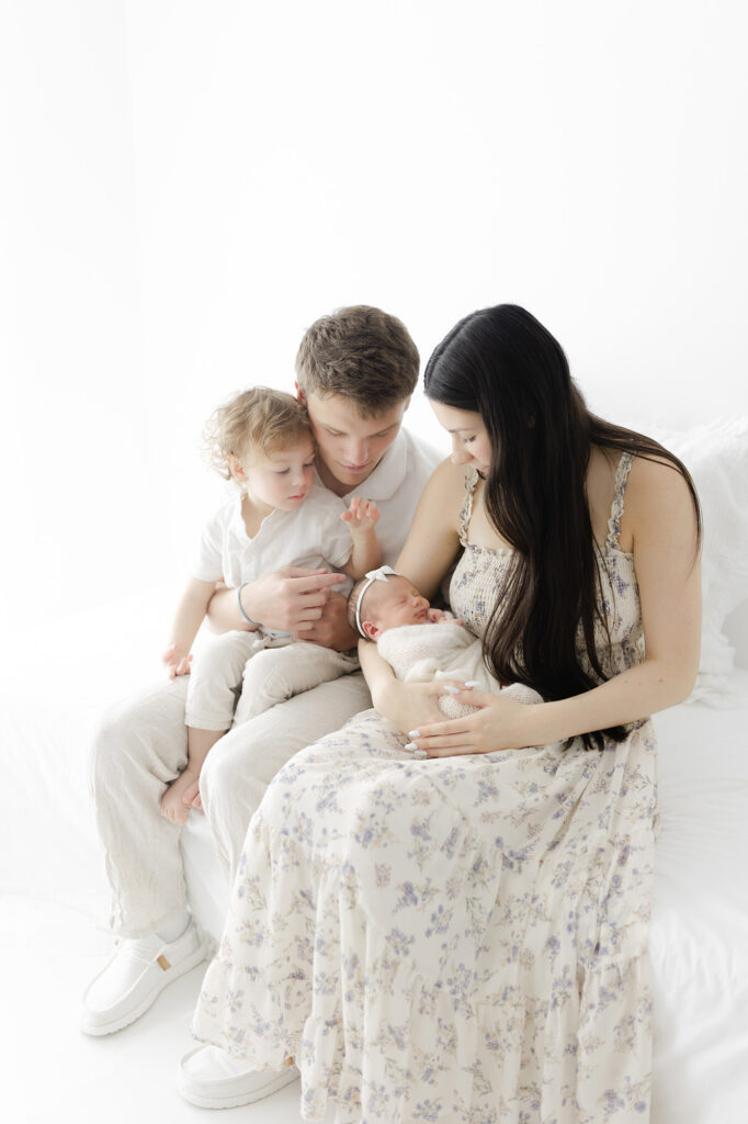 Family dressed in soft neutrals and pastels, showing what to wear for newborn photos.