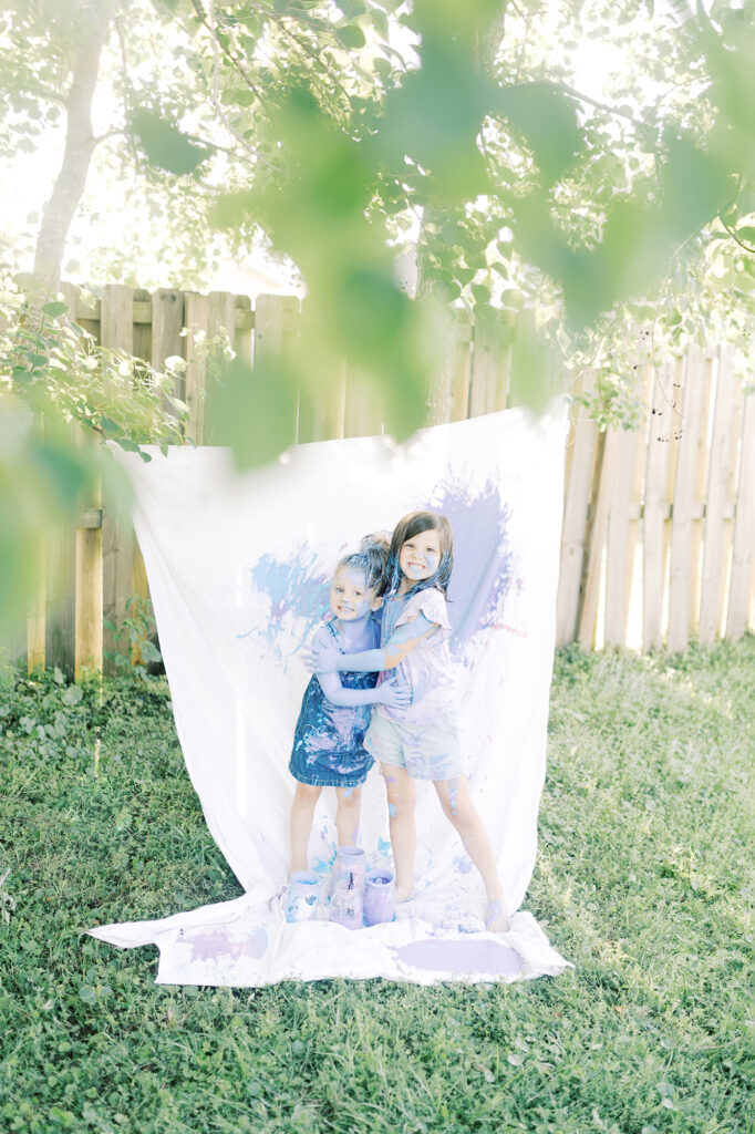 Two sisters covered in paint hugging each other after their photo session.