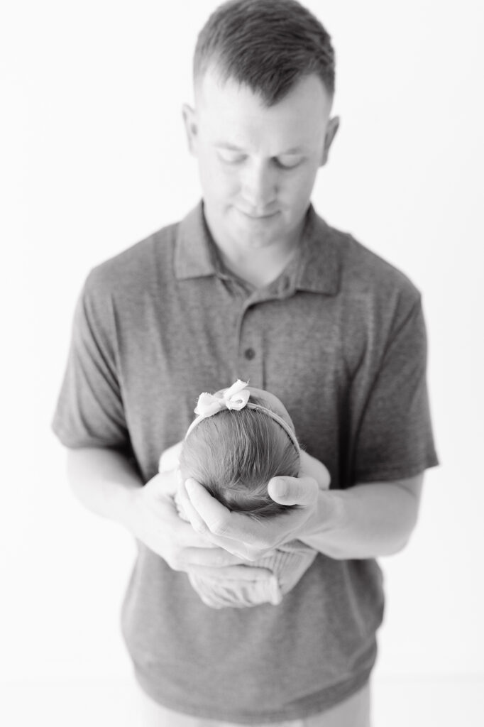 Dad holding newborn highlighting how small baby is during newborn photo session