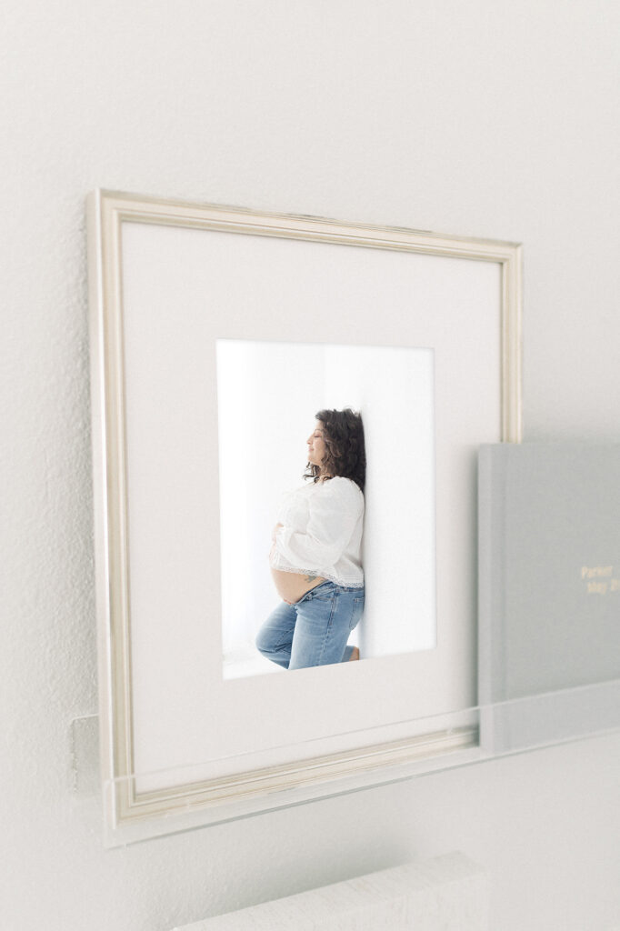 A framed photo on a shelf displaying a maternity photo from a photographer in grand forks, nd.