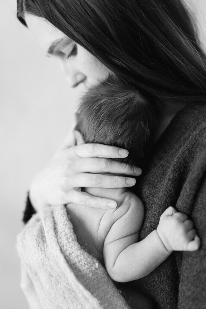 Mother holding newborn close in a natural, comforting pose
