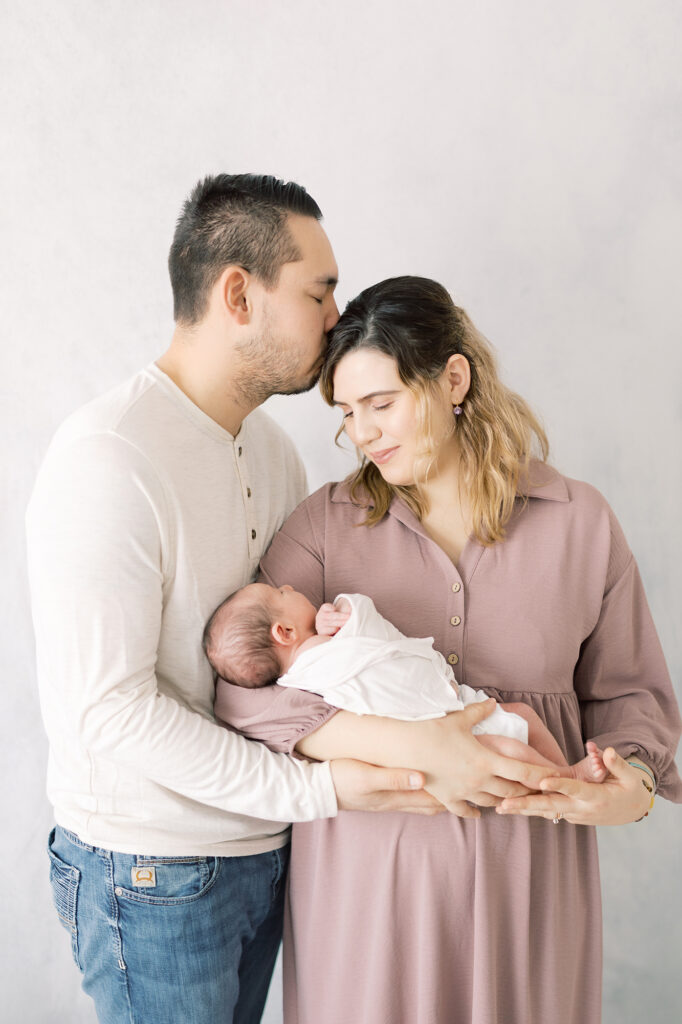 Parents holding newborn together in a timeless family photography pose
