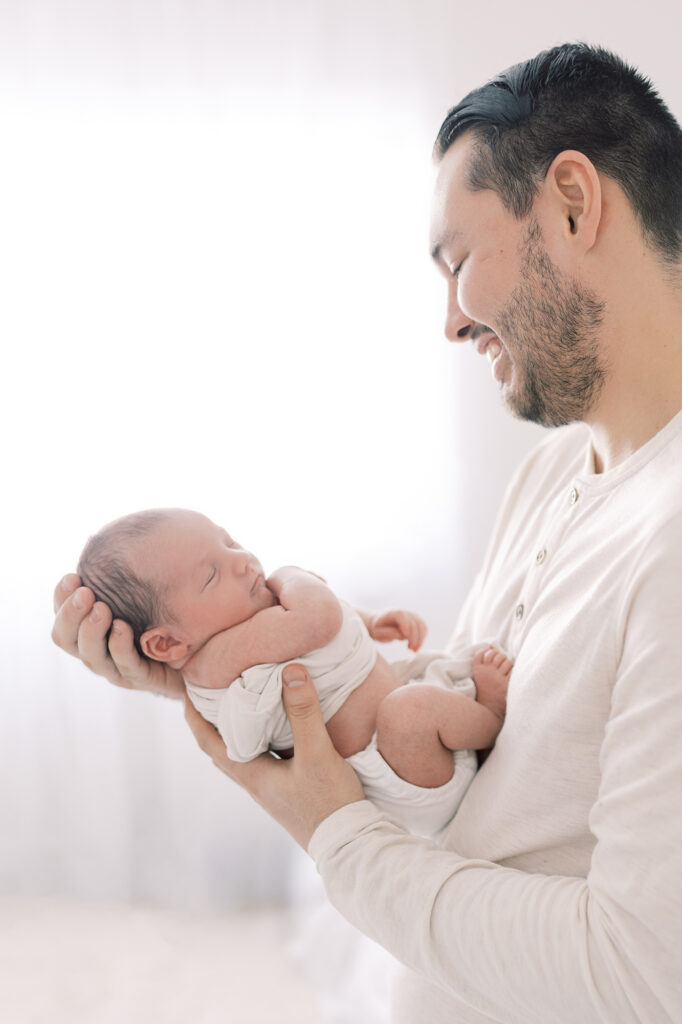 Dad holding newborn highlighting how small baby is during newborn photo session