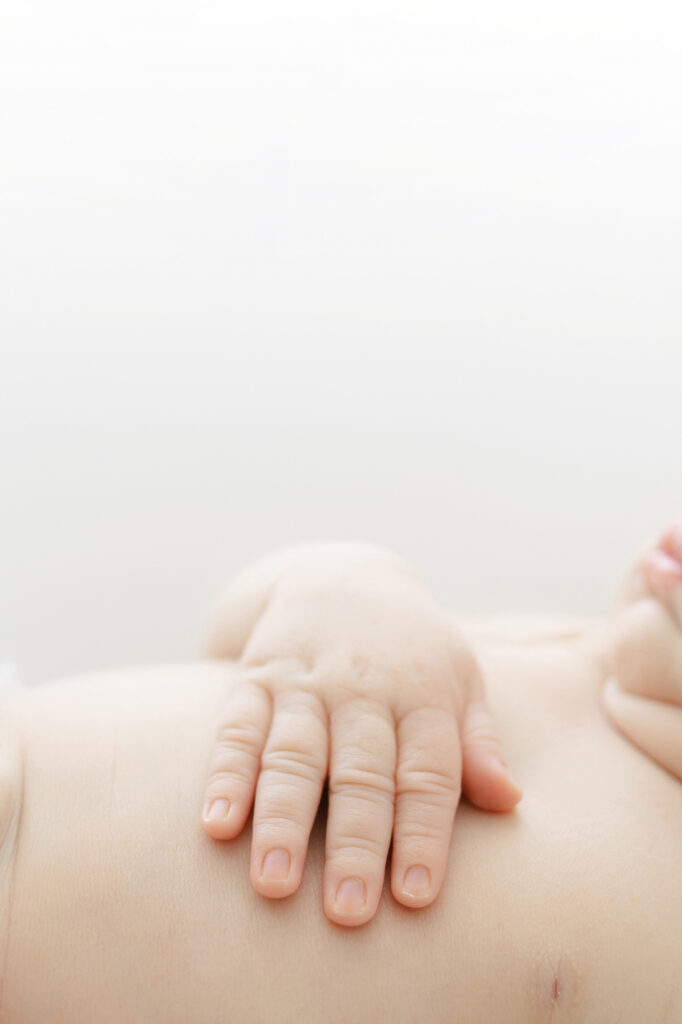 Newborn photography detail shot capturing baby’s hands and texture